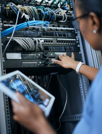 Rearview shot of an unrecognizable female programmer working on a tablet in a server room.