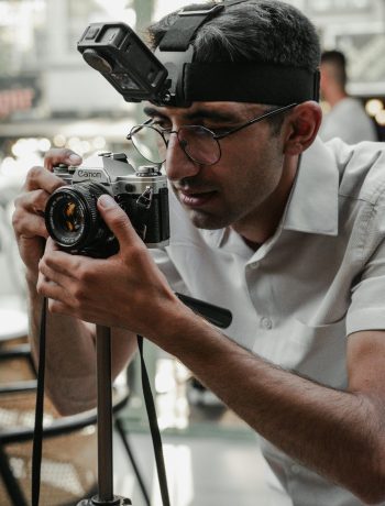 A male photographer using a camera with a headlamp indoors in Ankara, Turkey.